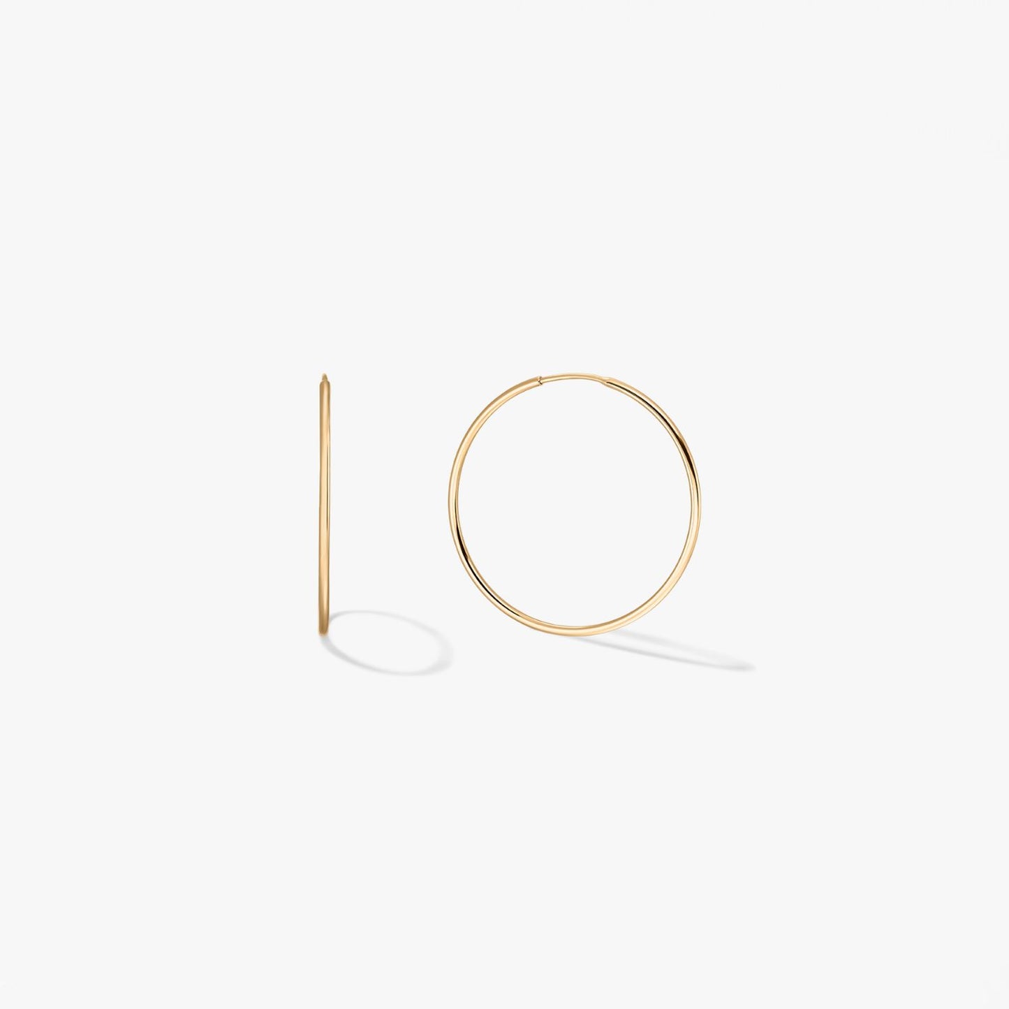 Pair of mini 14k yellow gold hoop earrings on a white background, one shown front-on and one in side profile.
