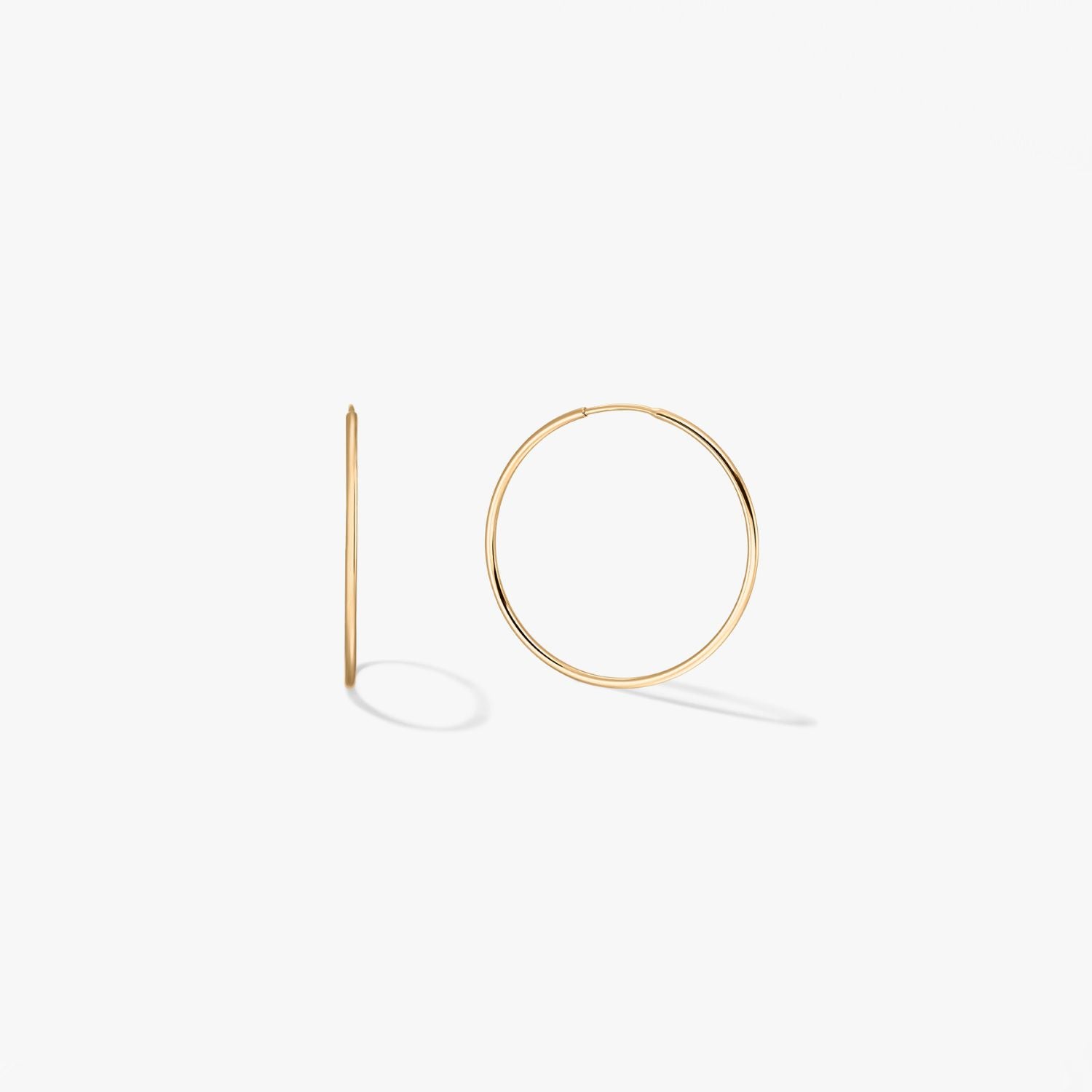 Pair of mini 14k yellow gold hoop earrings on a white background, one shown front-on and one in side profile.