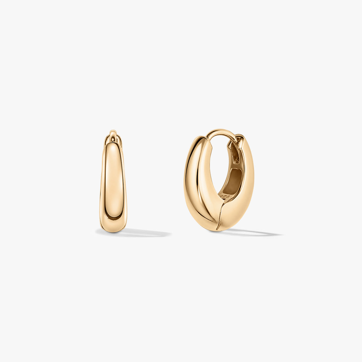 Pair of small golden mini dome huggie hoop earrings on a white background.