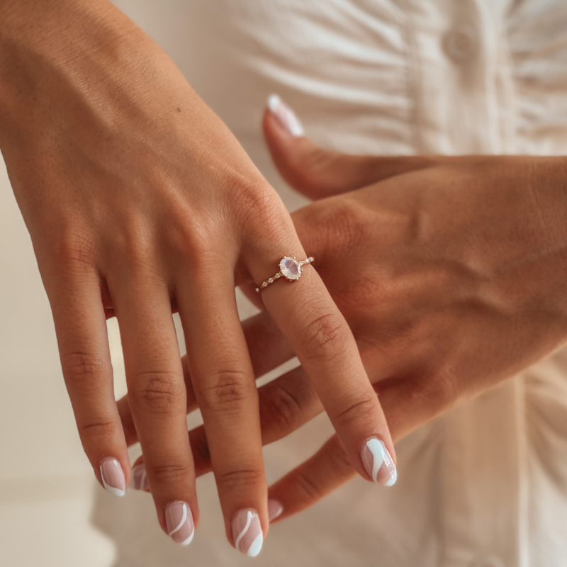 Close-up of hands with nail art wearing a rose gold moonstone ring.