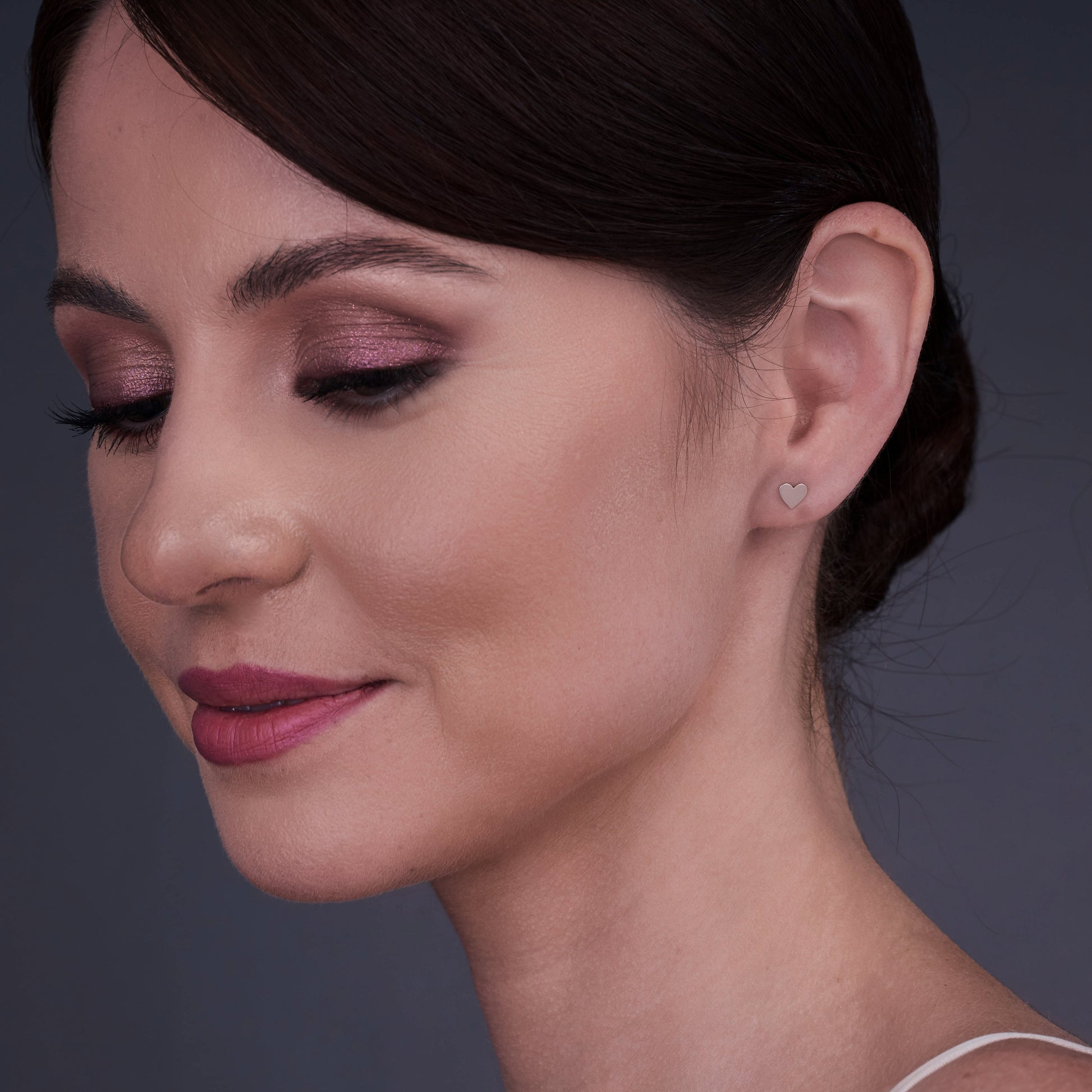 Woman wearing 14K gold heart-shaped earrings with closed eyes and a calm expression.