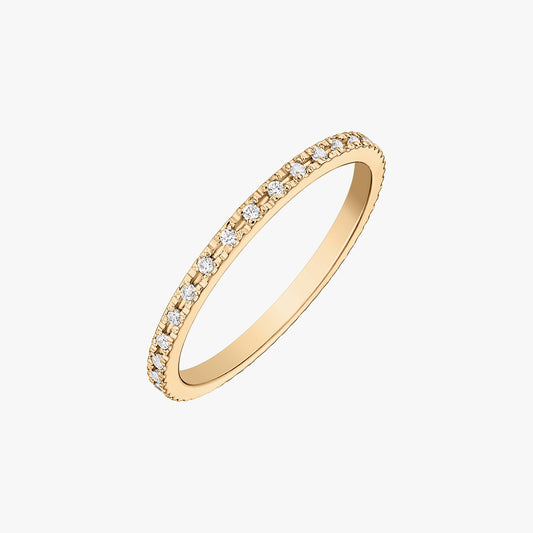 Slim tennis wedding band in 14K yellow gold set with round white zirconia stones, isolated on a white background.