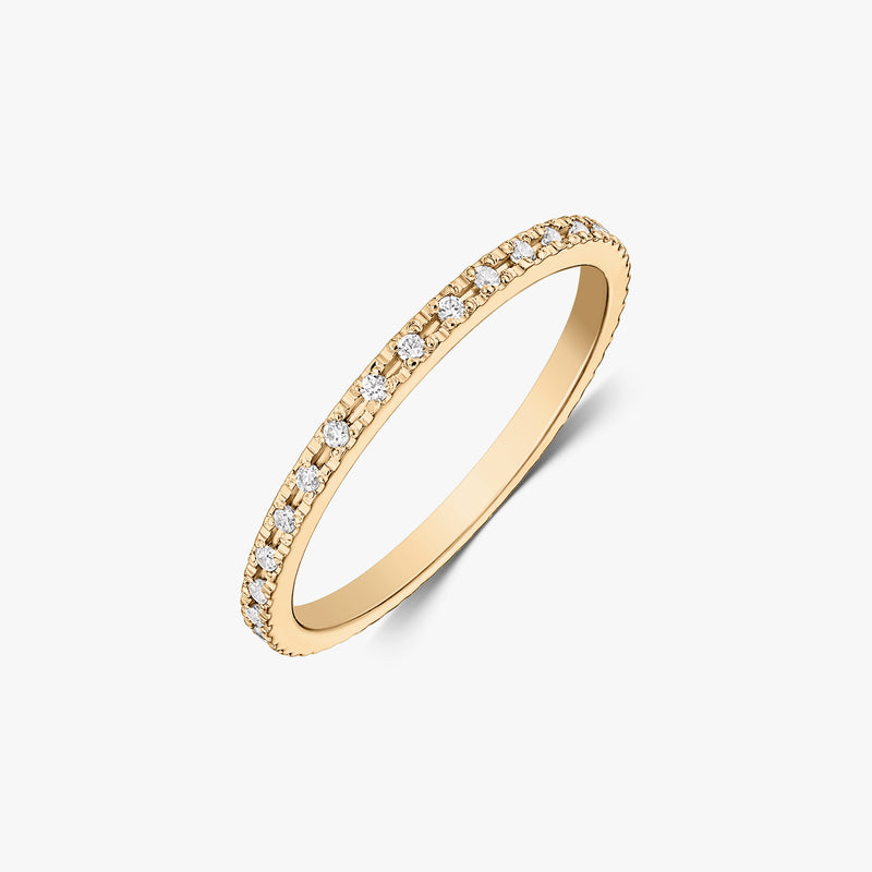 Slim tennis wedding band in 14K yellow gold with pavé-set white zirconia stones, photographed on a white background.