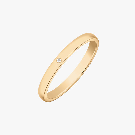 Slim 14K yellow gold wedding band with a small round diamond accent, photographed on a white background.