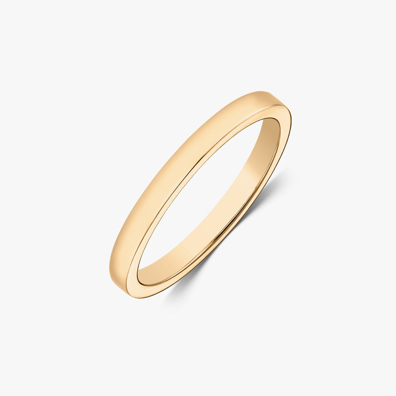 Angled studio shot of a slim 14k yellow gold polished band ring on a white background.