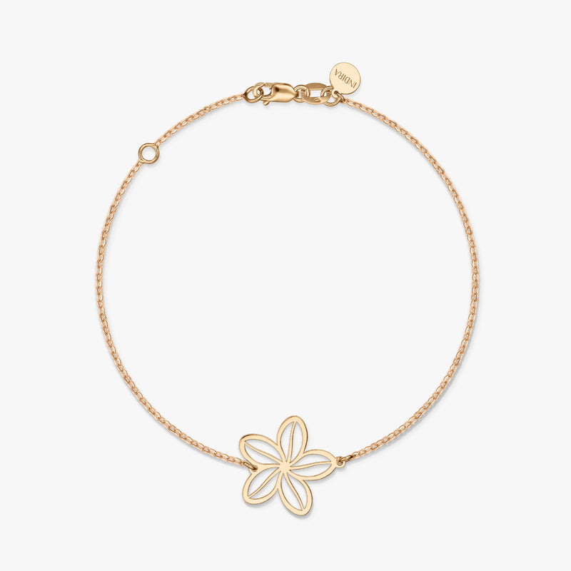 A minimalist gold bracelet featuring a delicate flower charm on a solid white background.