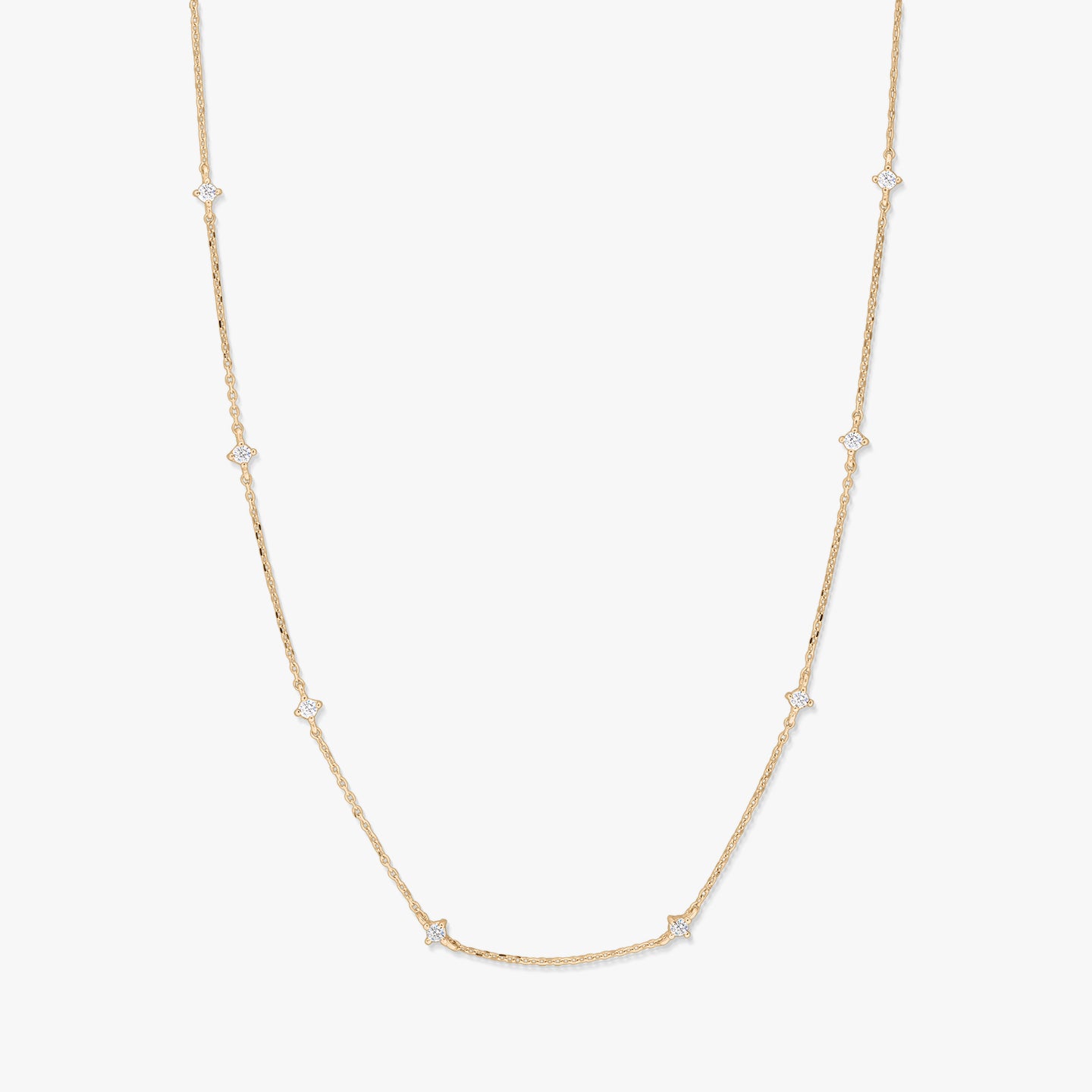 Delicate 14K yellow gold station necklace with small starburst-shaped white zirconia accents spaced along a fine chain, photographed on a white background.
