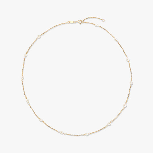 Elegáns 14K sárga arany station nyaklánc, apró, természetes fehér gyöngyökkel a finom láncon egyenletesen elhelyezve, fehér háttéren.