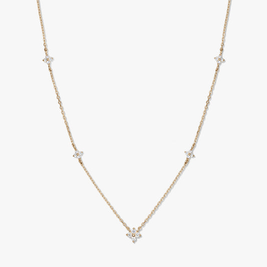 Delicate 14K yellow gold station necklace with small white zirconia clover motifs on a fine chain, photographed on a white background.