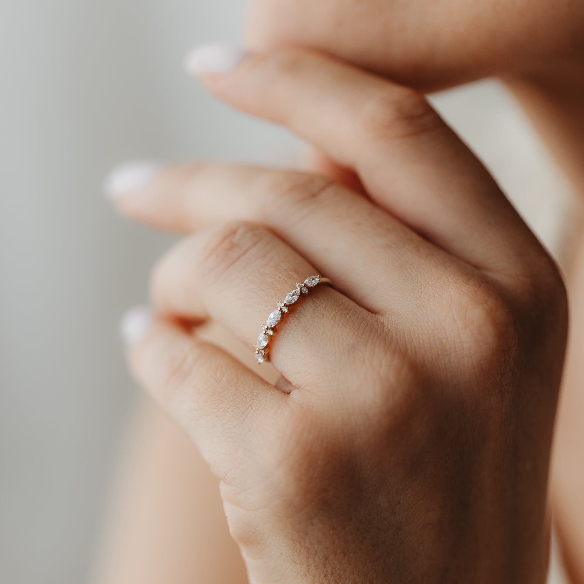 Close-up of a hand wearing the Fiorelle yellow gold diamond ring with alternating marquise and round stones.