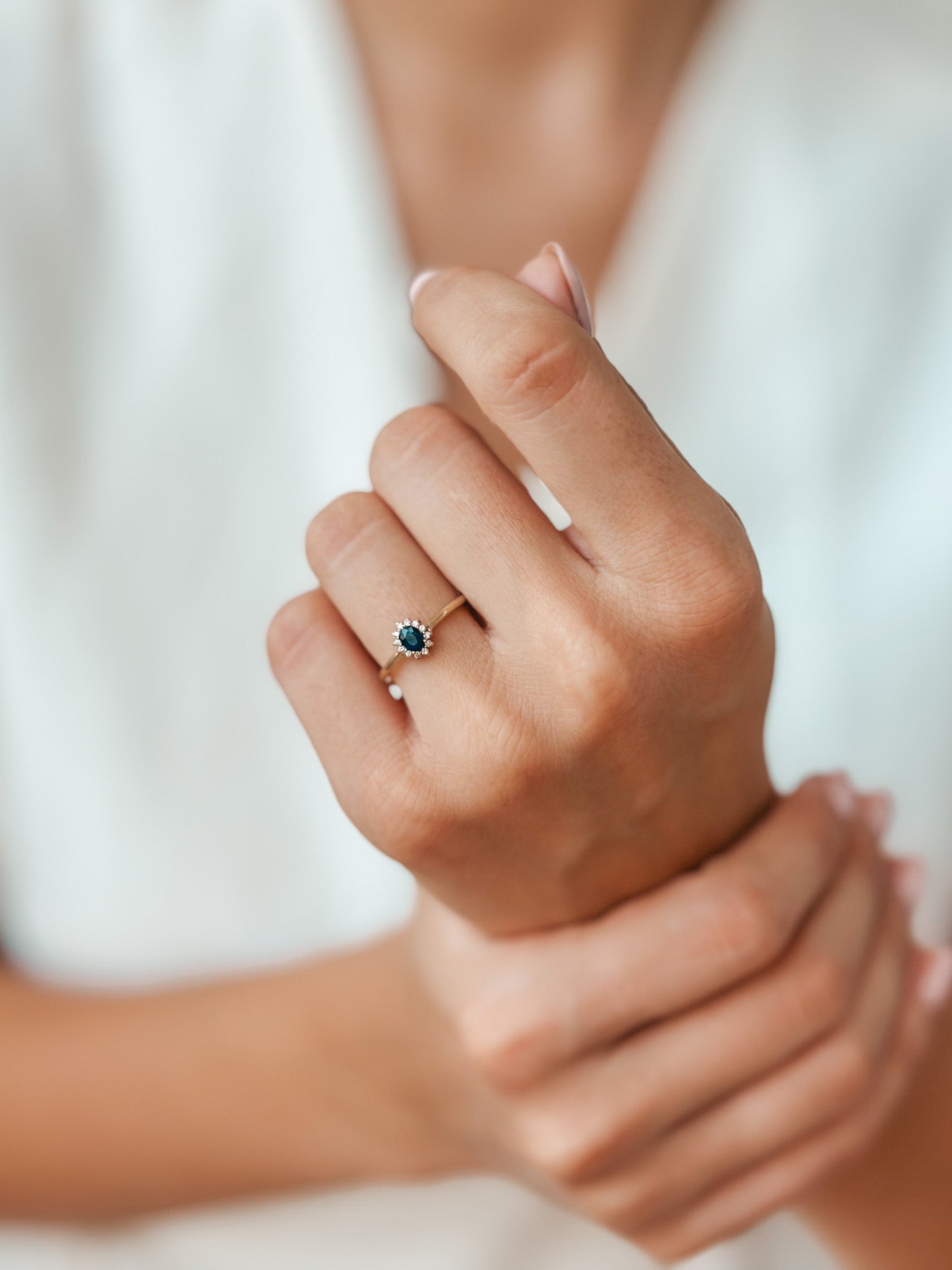 Close-up of a hand wearing a Genn Gold Ring featuring sapphire and diamonds.