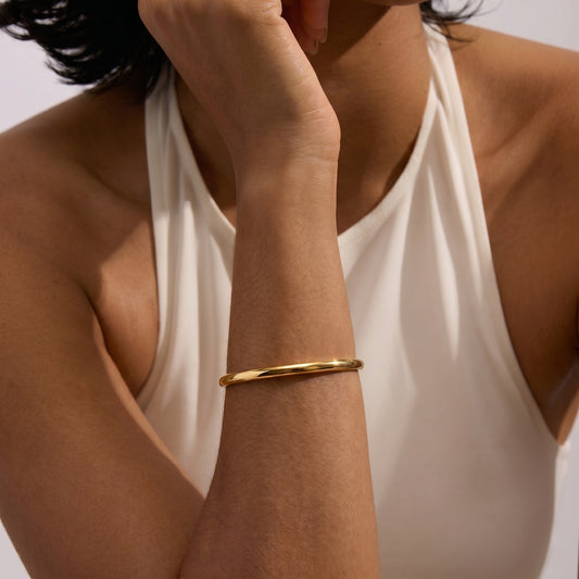 Close-up of a person wearing a Serena Golden Silver Bracelet on their wrist against a light background.