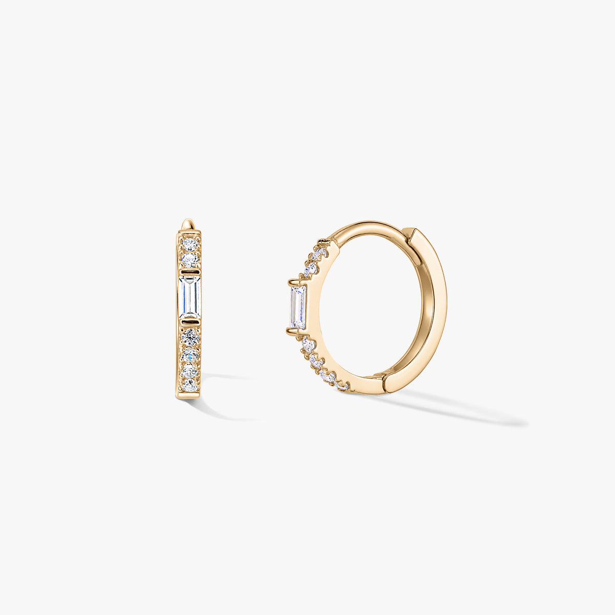 Pair of gold huggie hoop earrings with clear zirconia pavé and a vertical baguette accent, shown on a white background.
