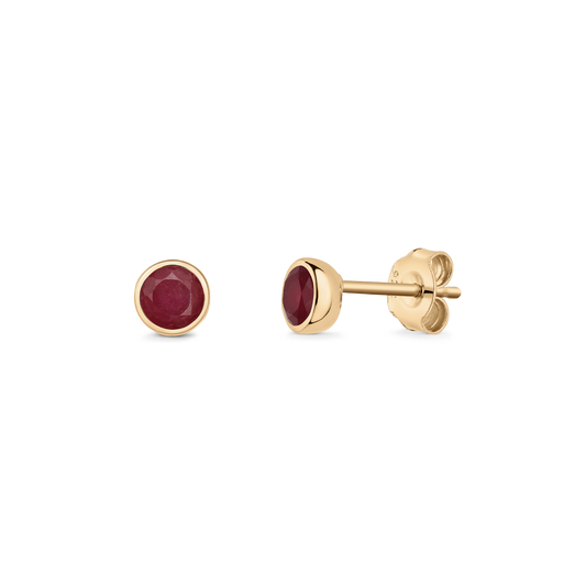 Pair of silver stud earrings with round ruby birthstones in gold‑tone bezel settings and butterfly backs, isolated on a transparent background.
