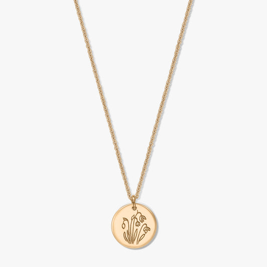 Gold‑plated sterling silver necklace with a round disc pendant engraved with the January birth flower snowdrop, shown on a white background.