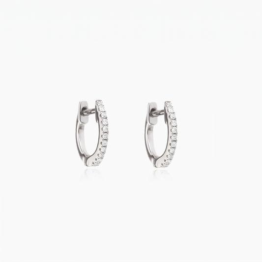 Pair of Sadie silver huggie hoop earrings with pavé clear zirconia on a white background.