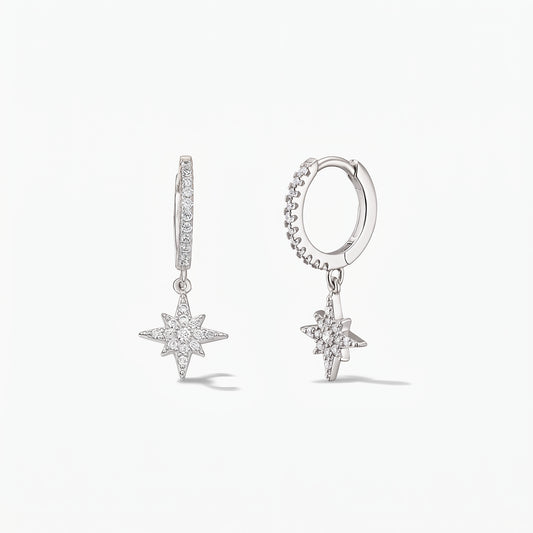 Pair of 925 sterling-silver huggie hoop earrings with pavé white zirconia North Star charms on a white background.