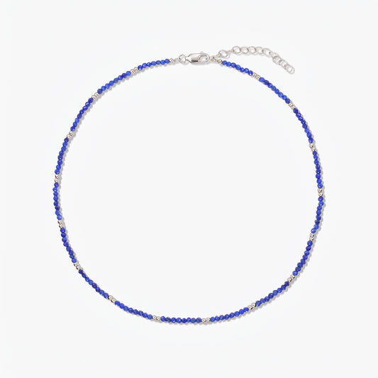Indira SummerScape ezüst nyaklánc kék lápisz lazuli gyöngyökkel, karabinerkapoccsal és lánchosszabbítóval fehér háttéren.